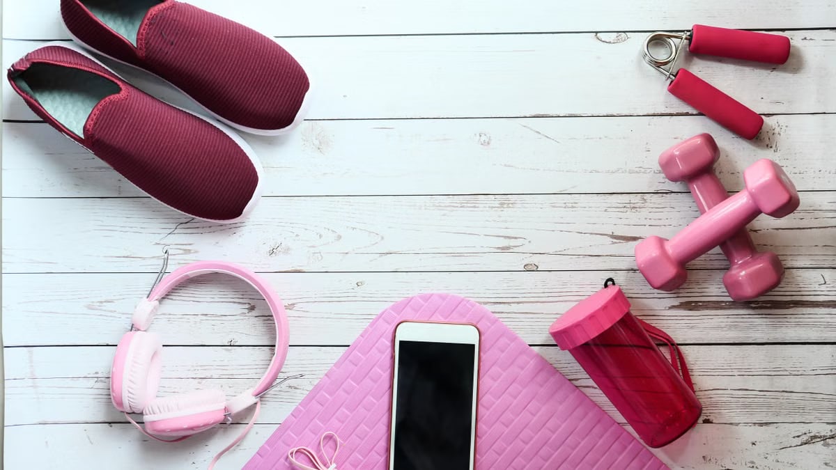 A flat lay of pink fitness items on white wood, ideal for lifestyle imagery.